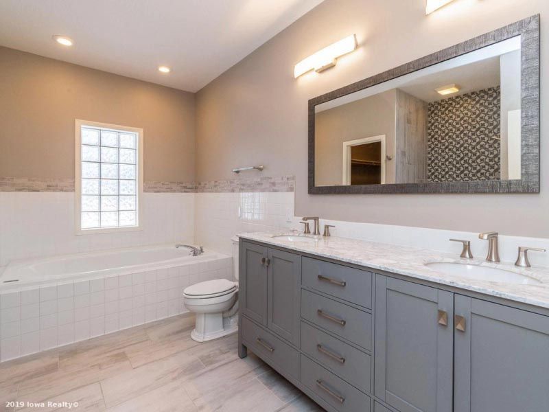 A bathroom with two sinks , a toilet , and a large mirror.