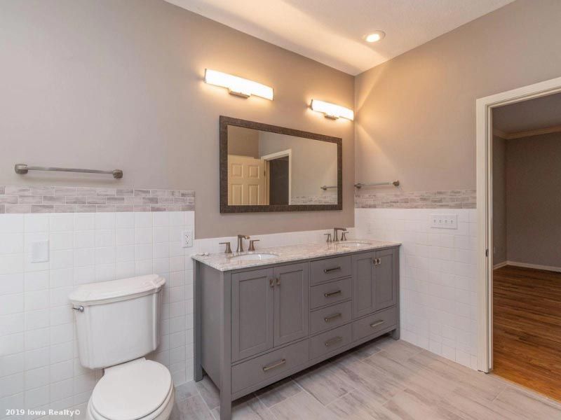 A bathroom with two sinks , a toilet and a mirror.