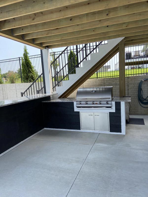 A patio with a grill and stairs in the background