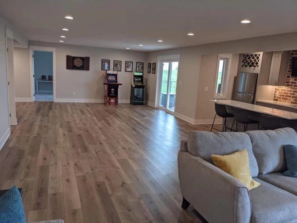 A living room with a couch , chair , and arcade machine.
