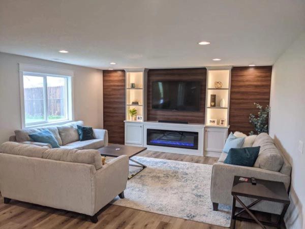 A living room with two couches , a fireplace and a flat screen tv.