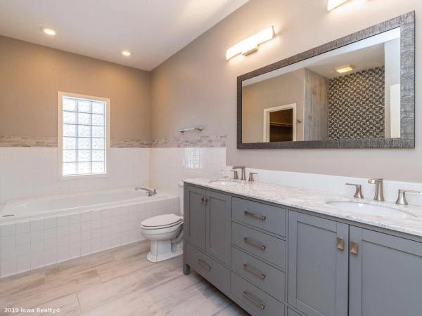 A bathroom with two sinks , a toilet , and a large mirror.