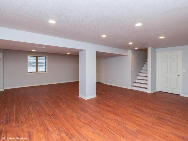 An empty basement with hardwood floors and stairs