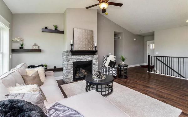 A living room with a fireplace and a ceiling fan.