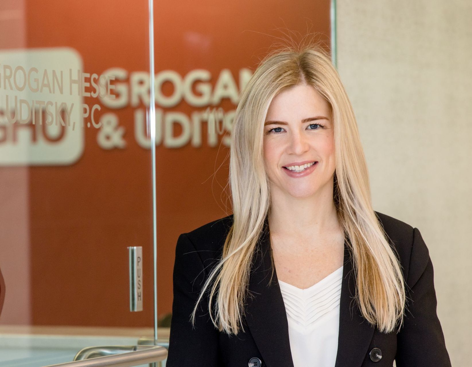 A woman is standing in front of a glass door that says grogan