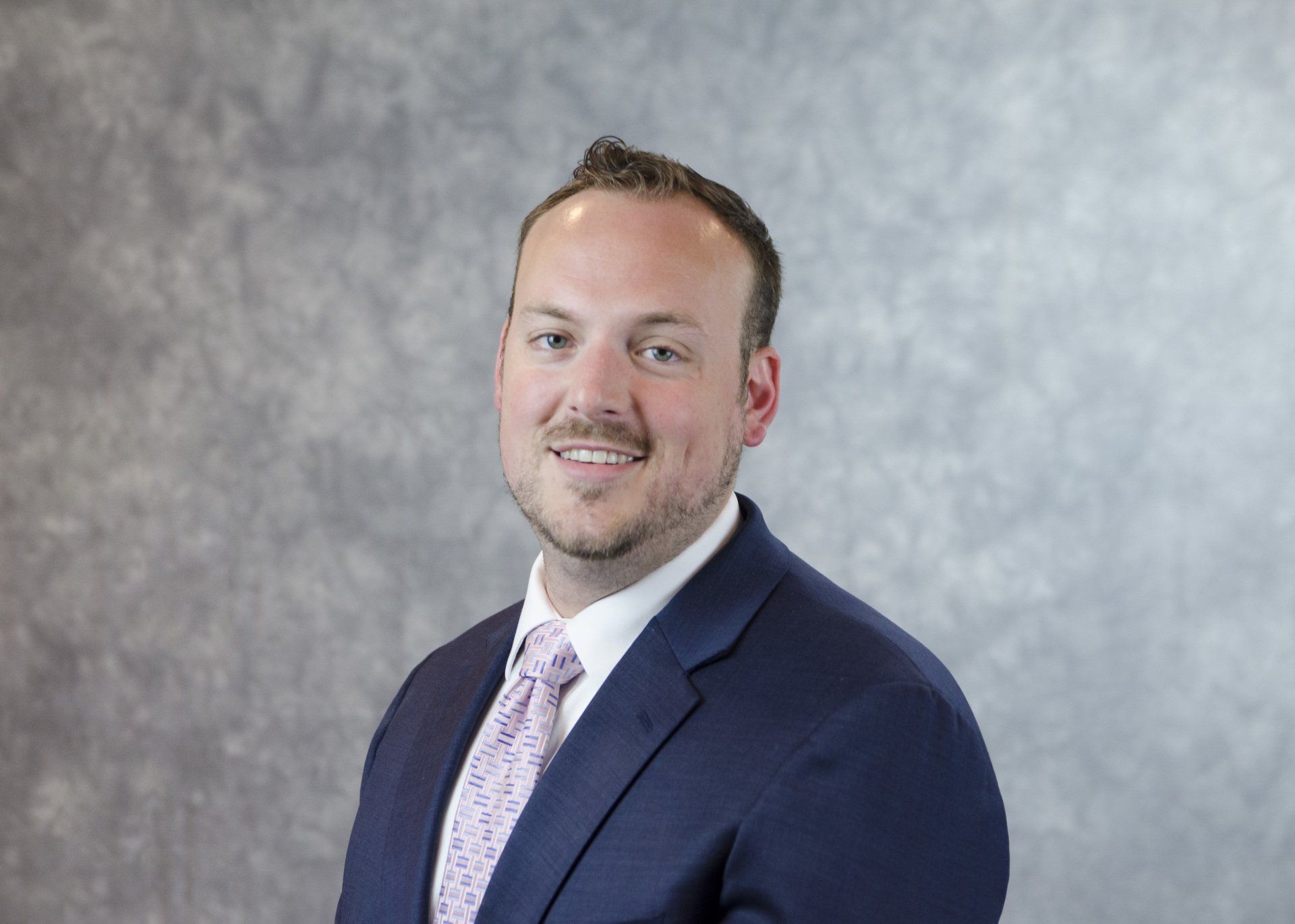 A man in a suit and tie is smiling for the camera.