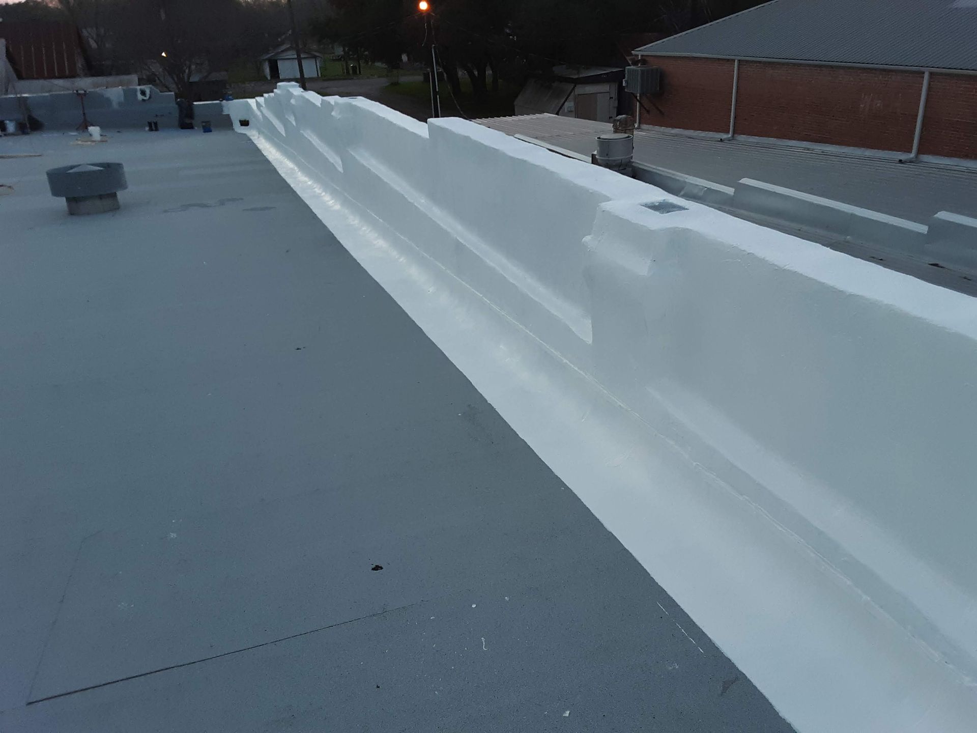 Gray rooftop with white parapet wall, exterior view.