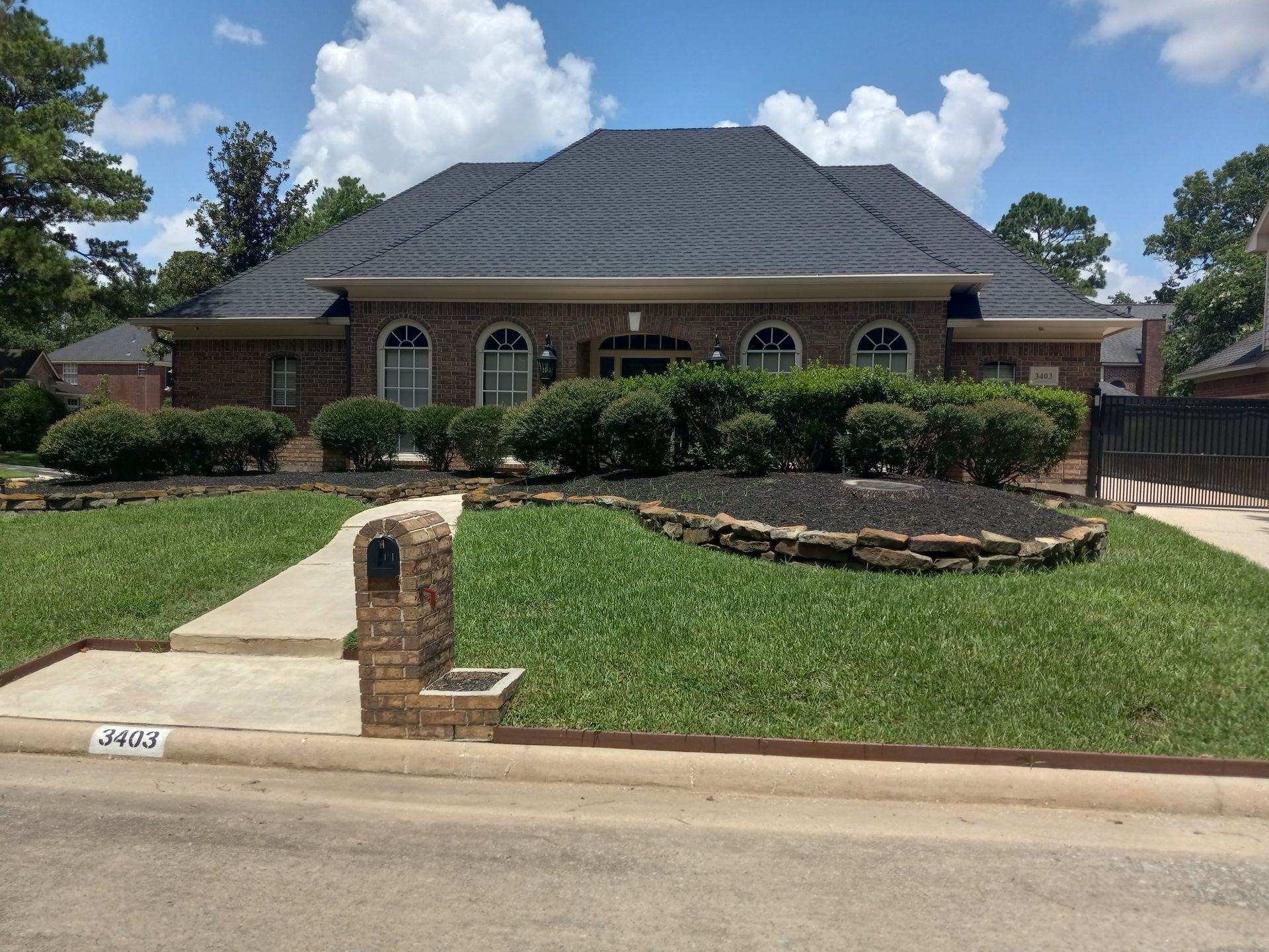 Brick house with a dark roof, arched windows, and well-manicured lawn.