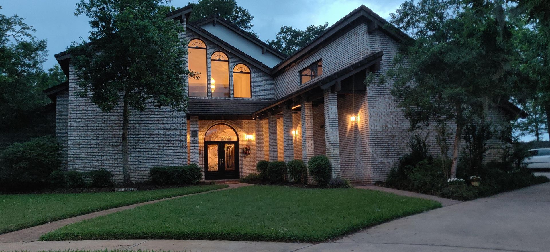 Large brick house at dusk, with arched windows and front door.