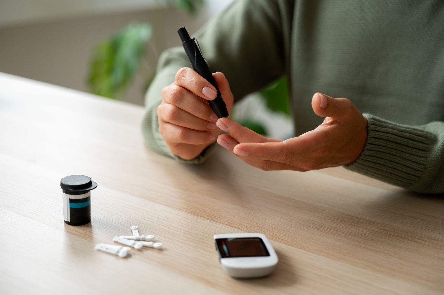 Person taking a blood glucose test at a table; testing kit, meter, and vials are visible.