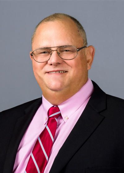 A man in a suit and tie is smiling for the camera