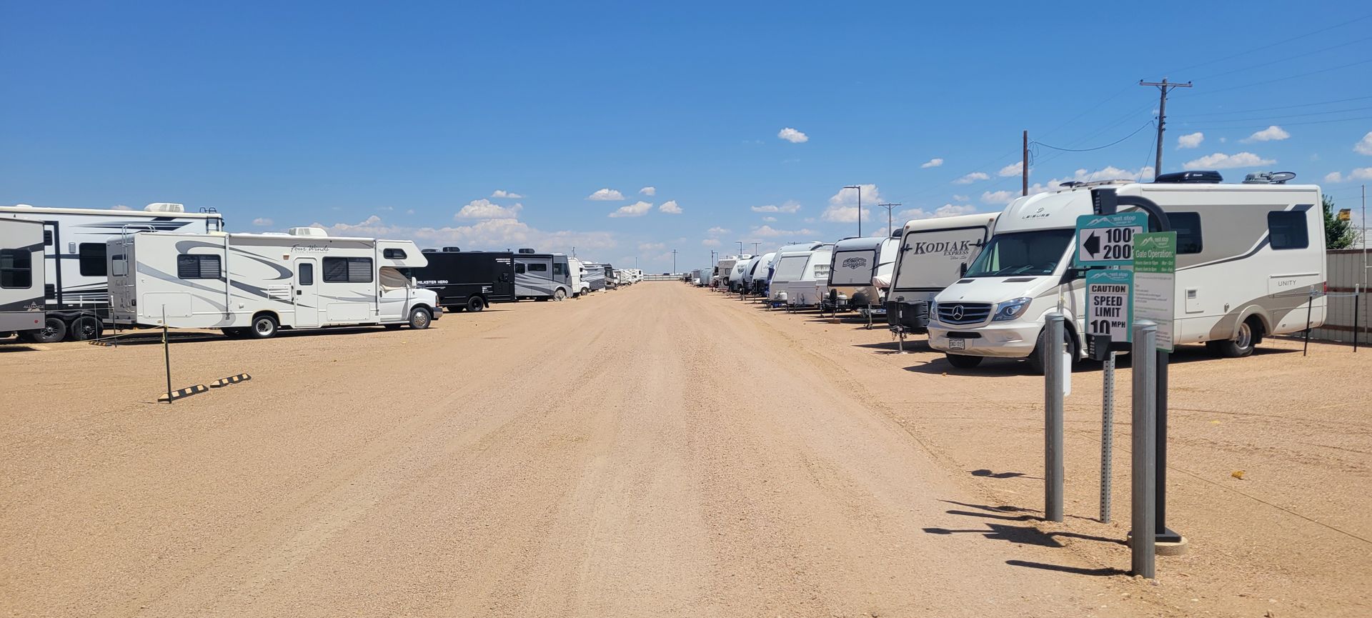 A row of rvs parked on the side of a dirt road.