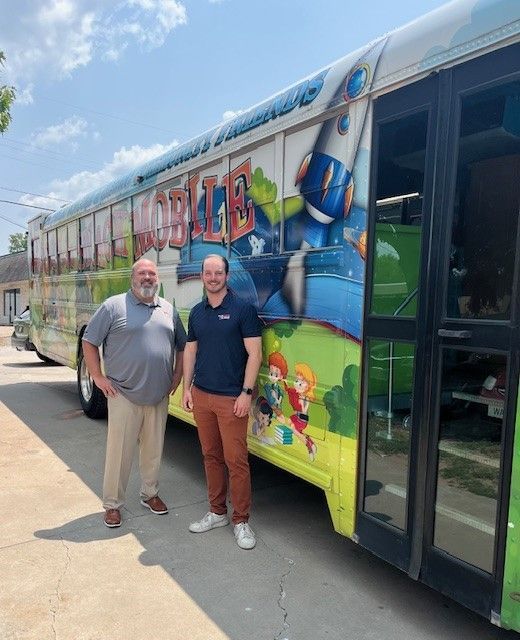 Two men stand in front of a colorful 