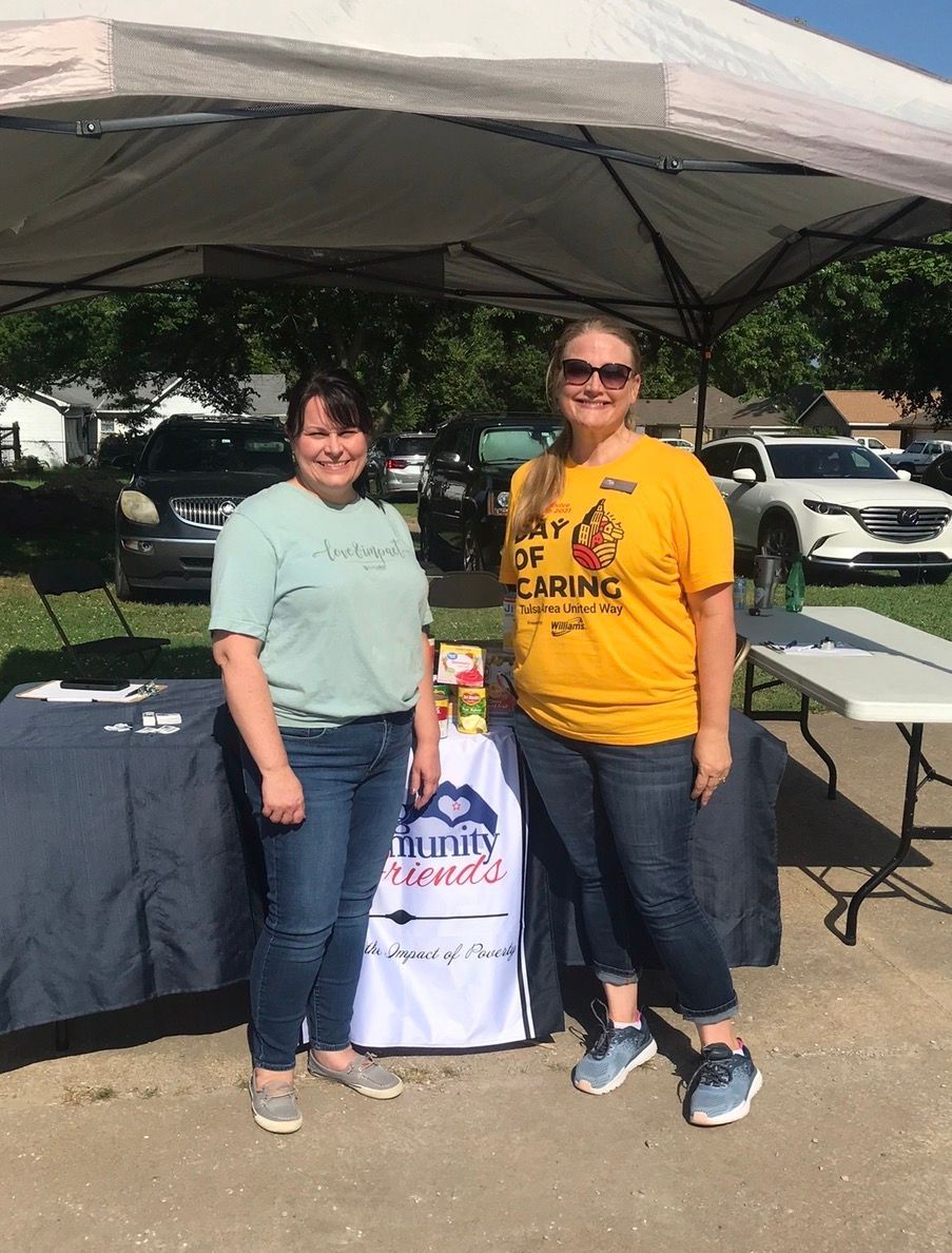 Two smiling individuals stand under a pop-up tent with a 