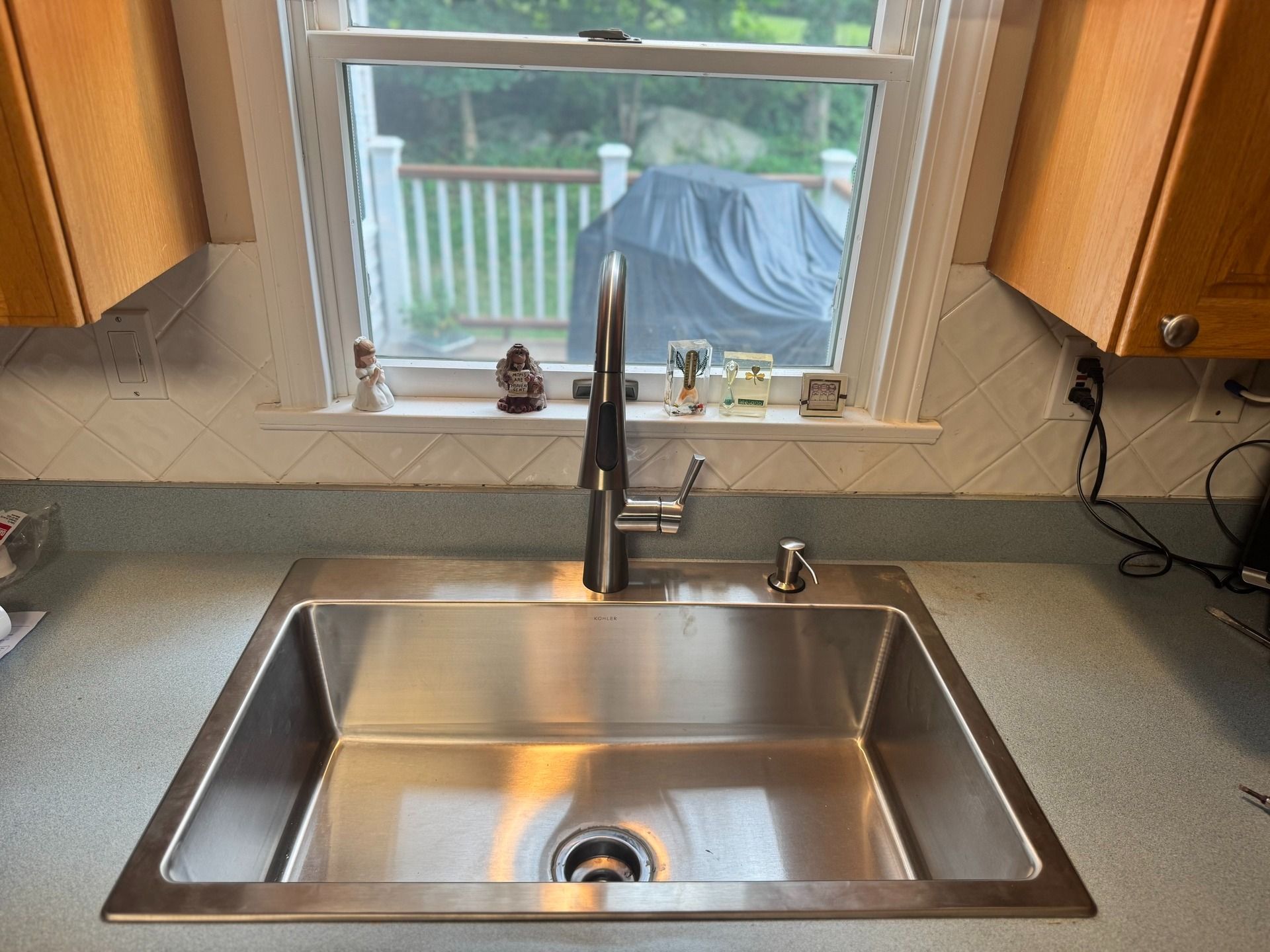 Stainless steel kitchen sink with a faucet in front of a window.