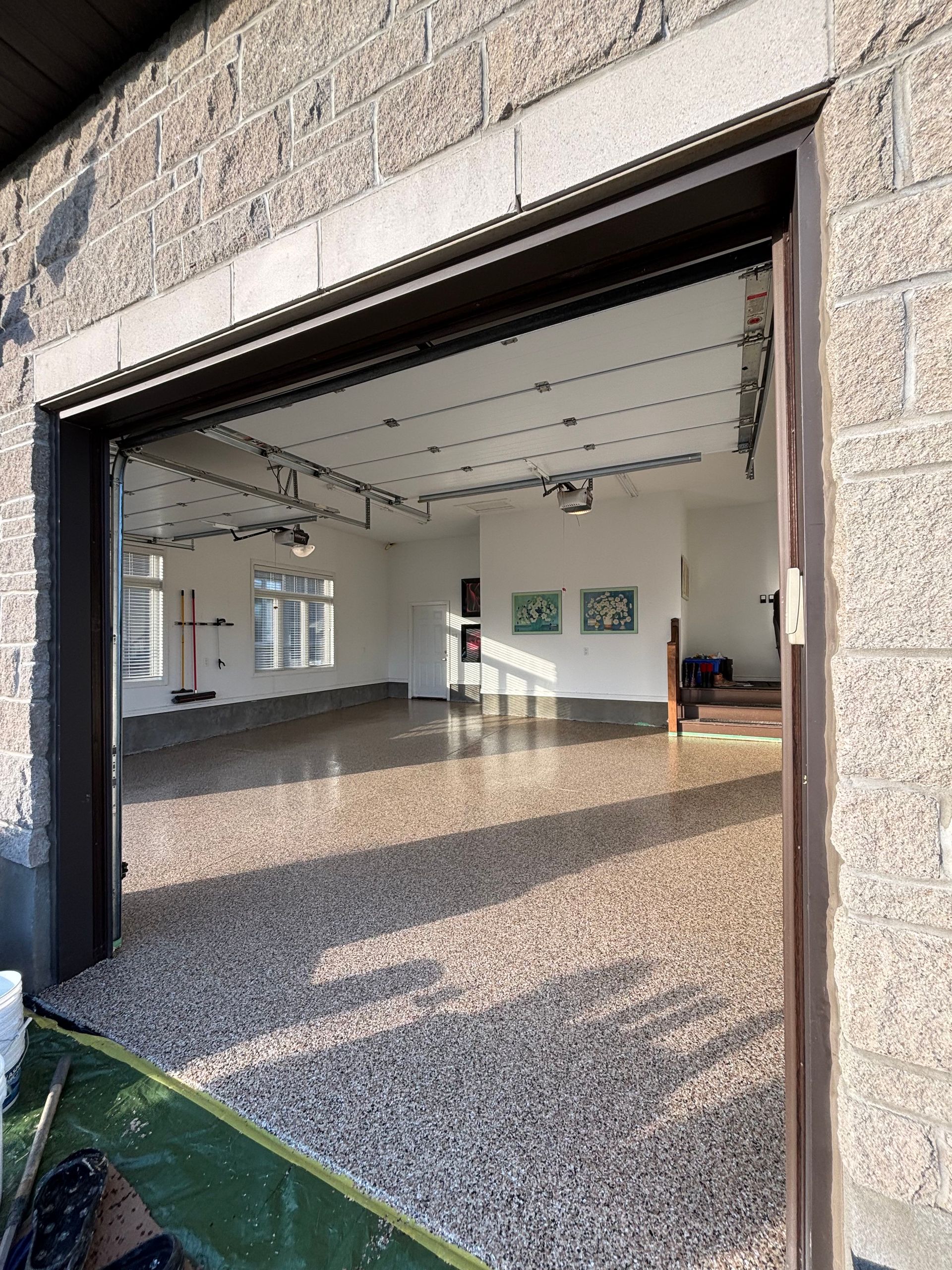 A garage door is open to a large empty room.