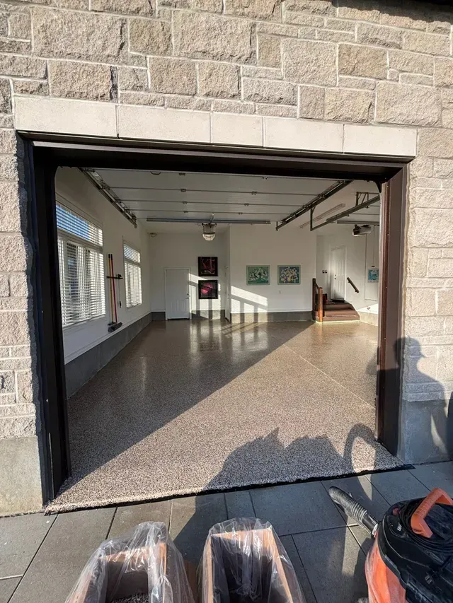 An open garage door with a vacuum cleaner in front of it