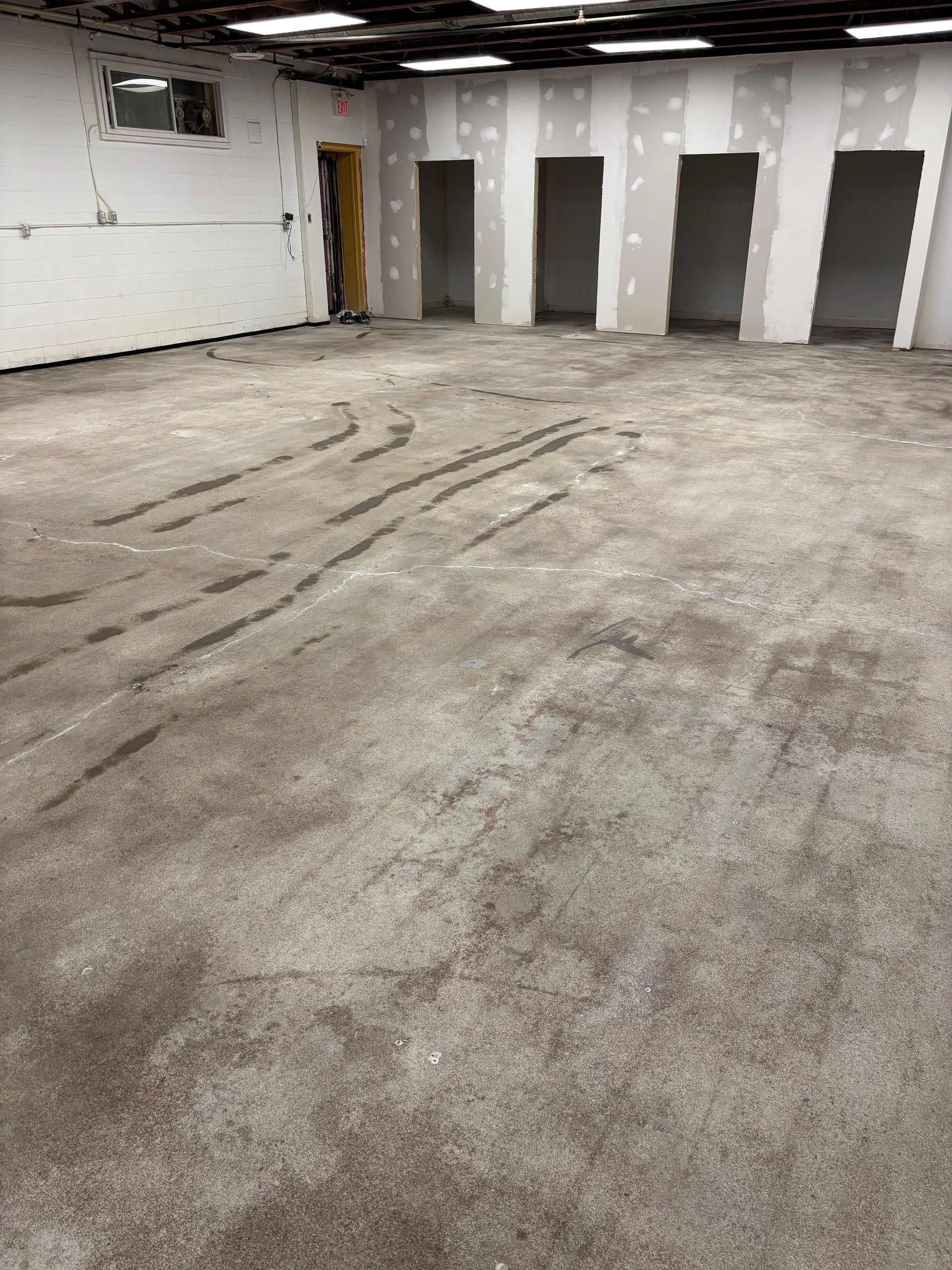 A large empty room with a concrete floor and white walls.