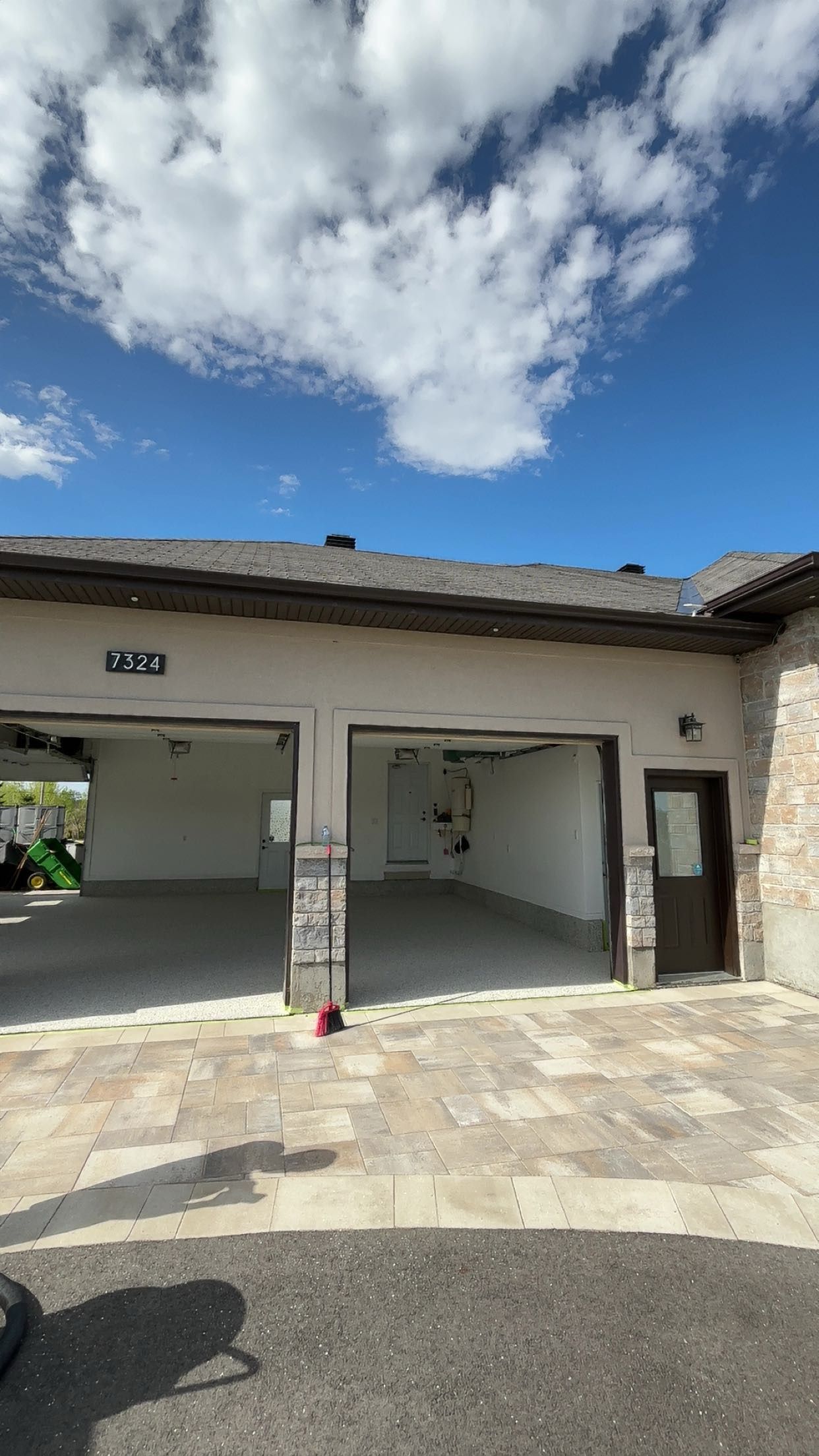 A large empty garage with two garage doors open on a sunny day.