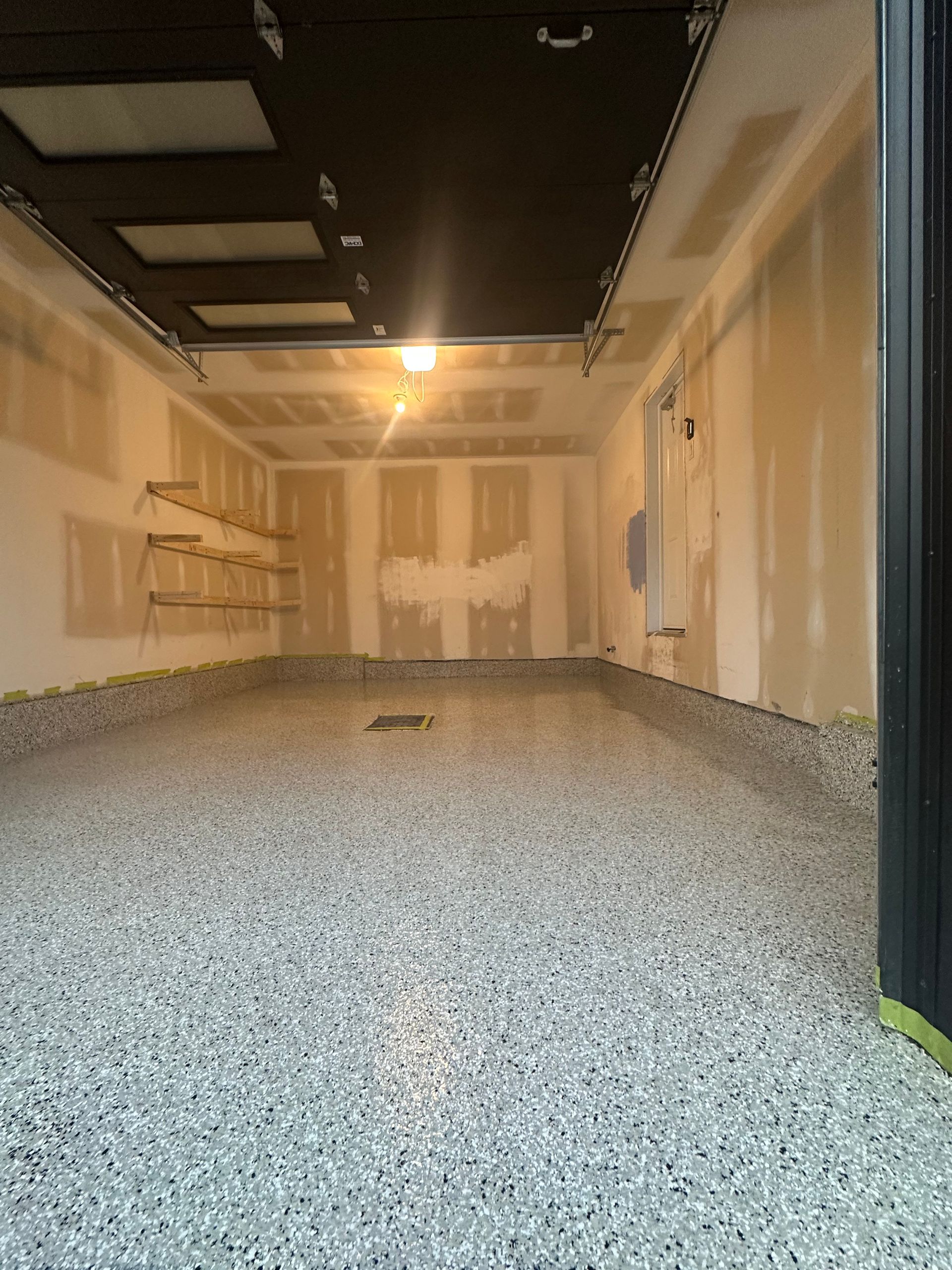 An empty garage with a gray floor and a black door