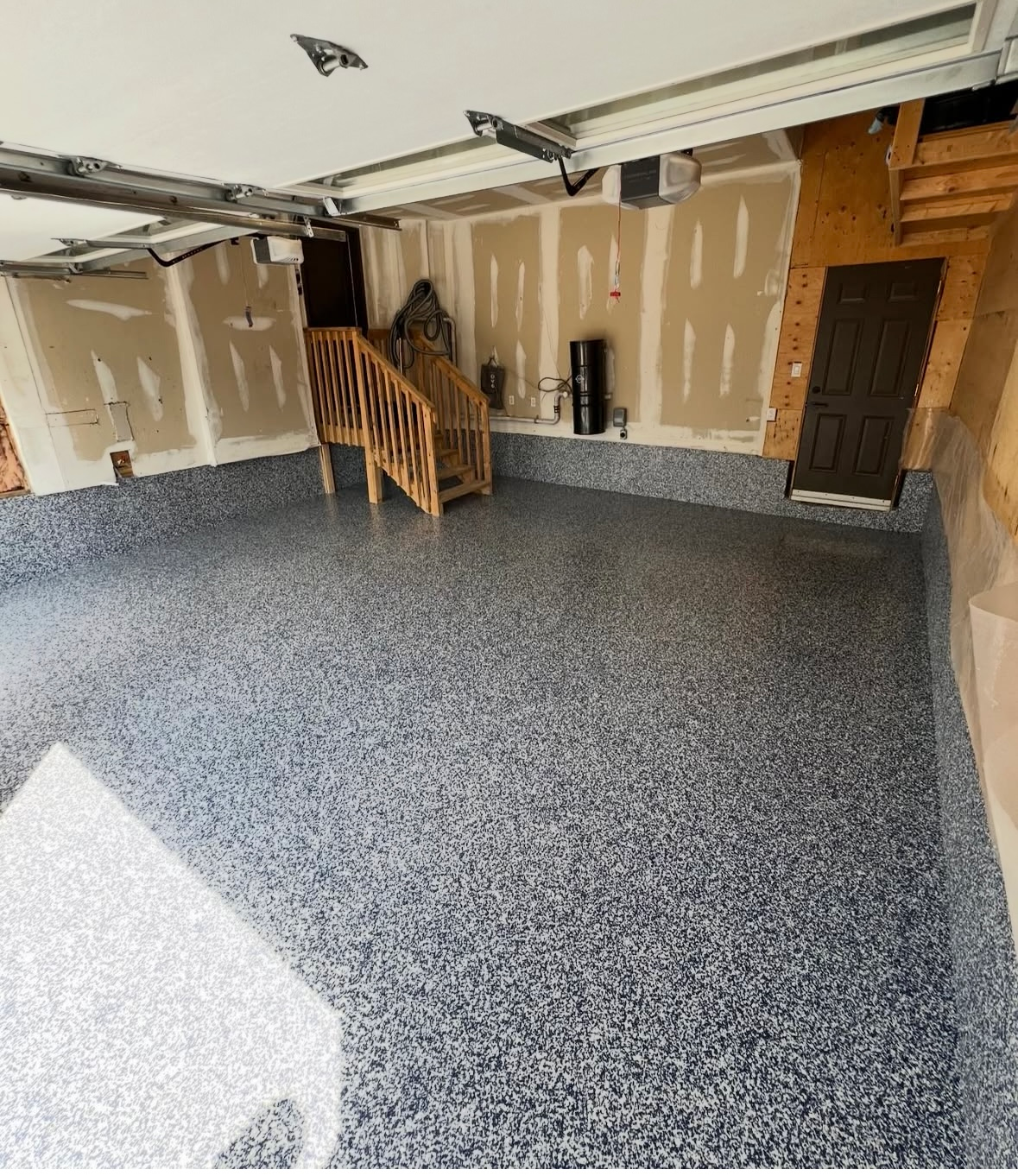 A garage with a staircase and a garage door open.