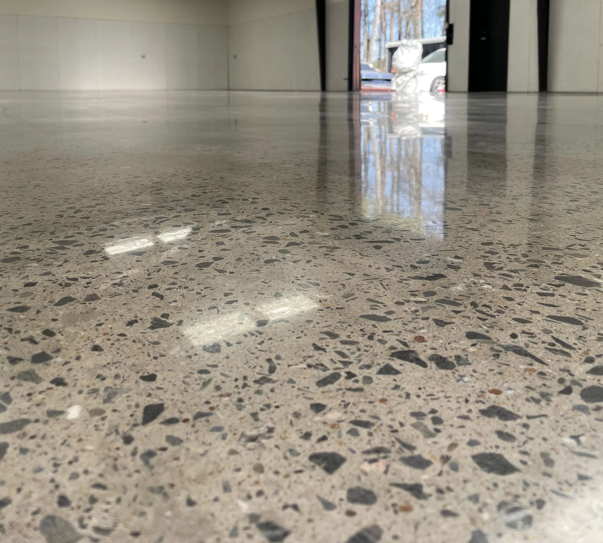 Garage with a speckled epoxy floor, open doors, and a worker.