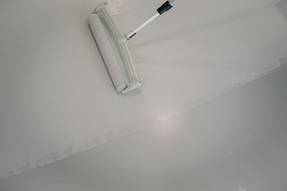 A person is painting a floor with a roller.