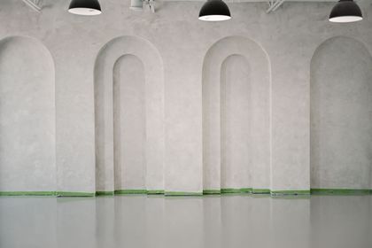 An empty room with arches on the walls and a concrete floor.