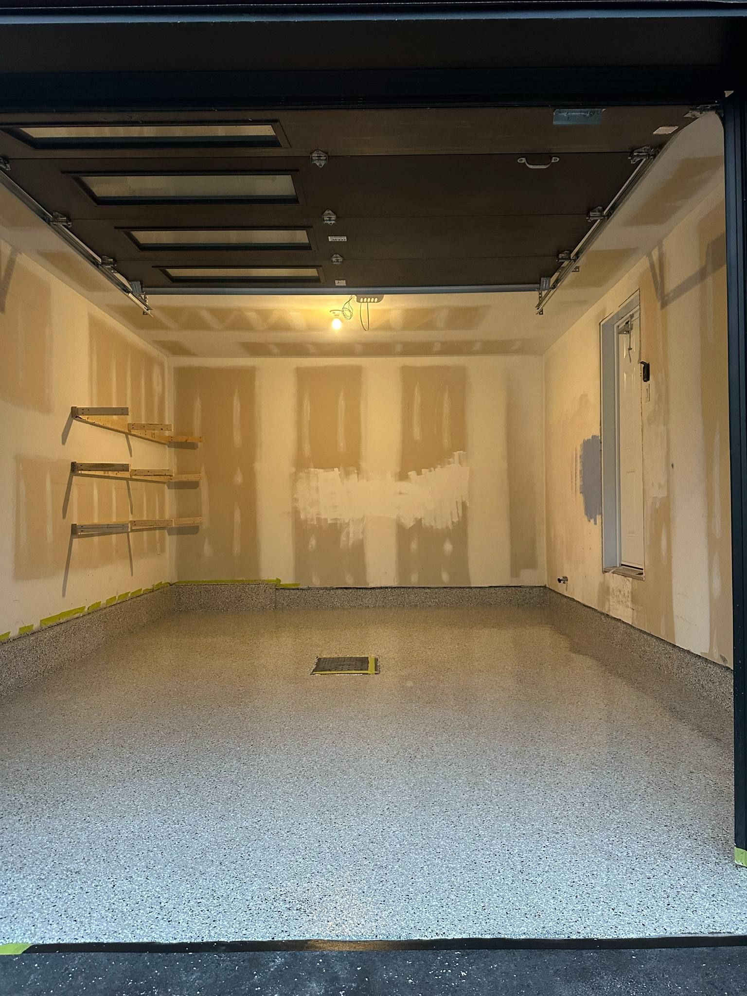 An empty garage with a black garage door and a concrete floor.