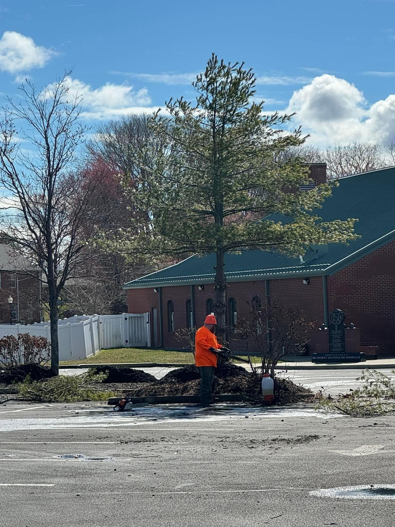 A man in an orange jacket is standing on the side of the road.
