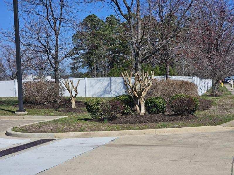 A white fence surrounds a park with trees and bushes.