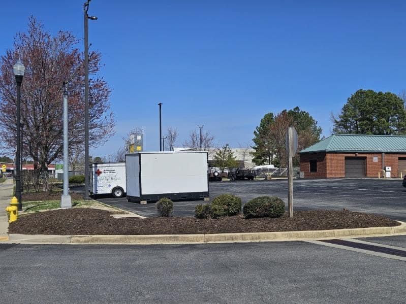 Two white trailers are parked in a parking lot next to a fire hydrant