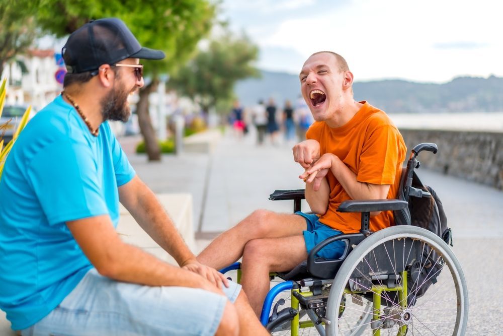 Man In Wheelchair Laughs With Another Man — Side By Side Support Services Casino in Casino, NSW