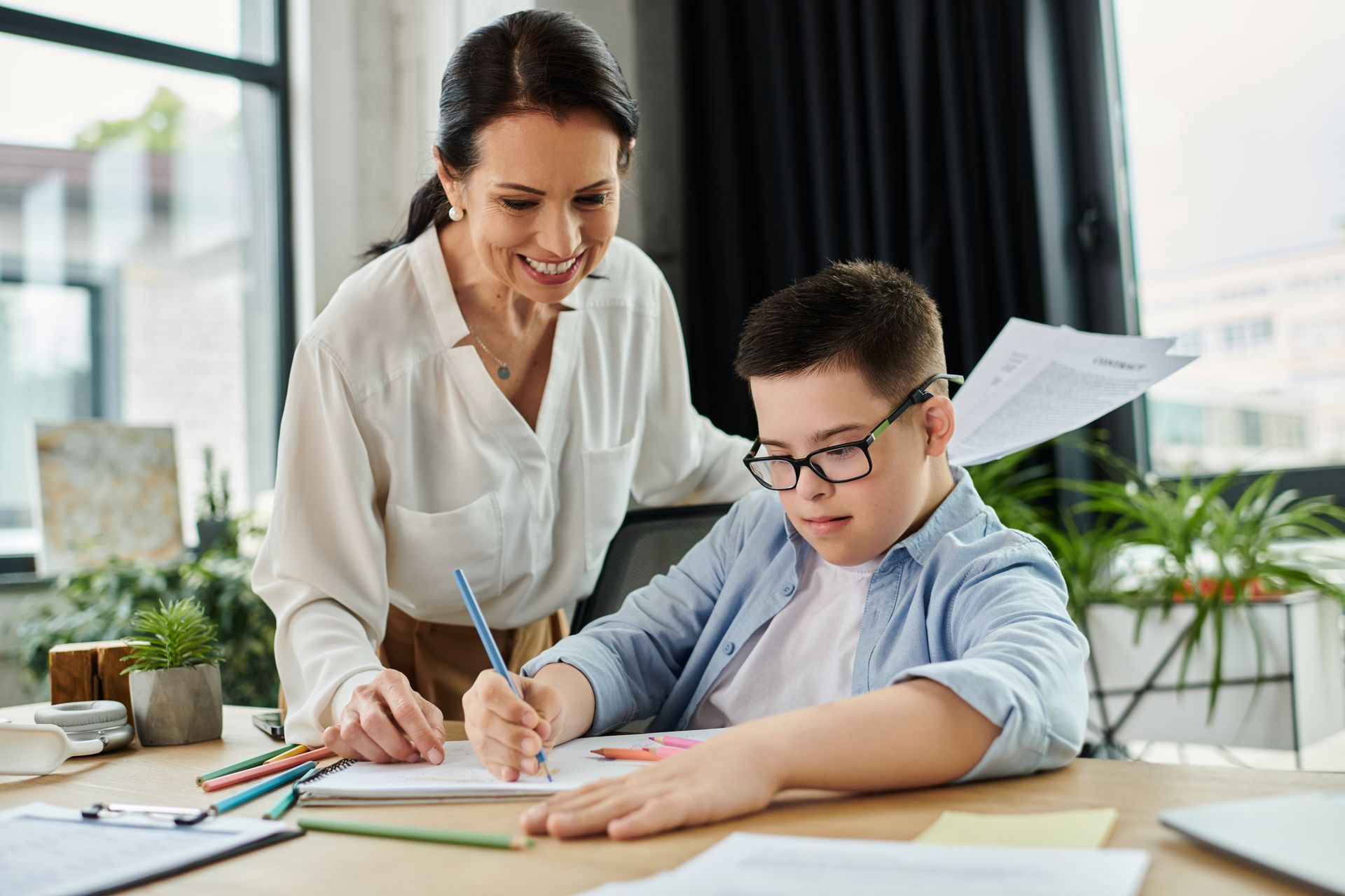 Woman Assists Boy With Glasses Writing At A Desk — Side By Side Support Services Casino in Casino, NSW