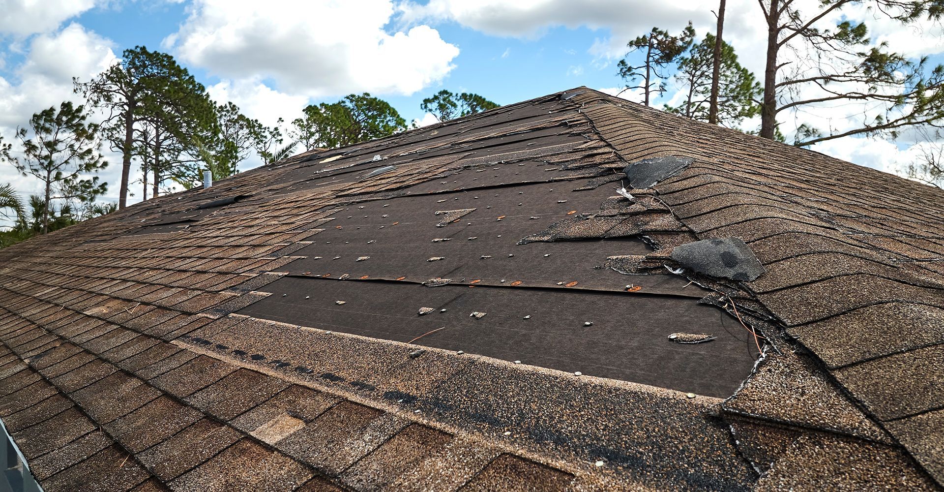 A roof with a hole in it and trees in the background