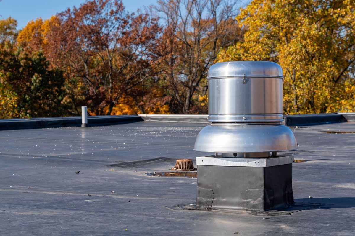 A roof with a chimney on it and trees in the background.