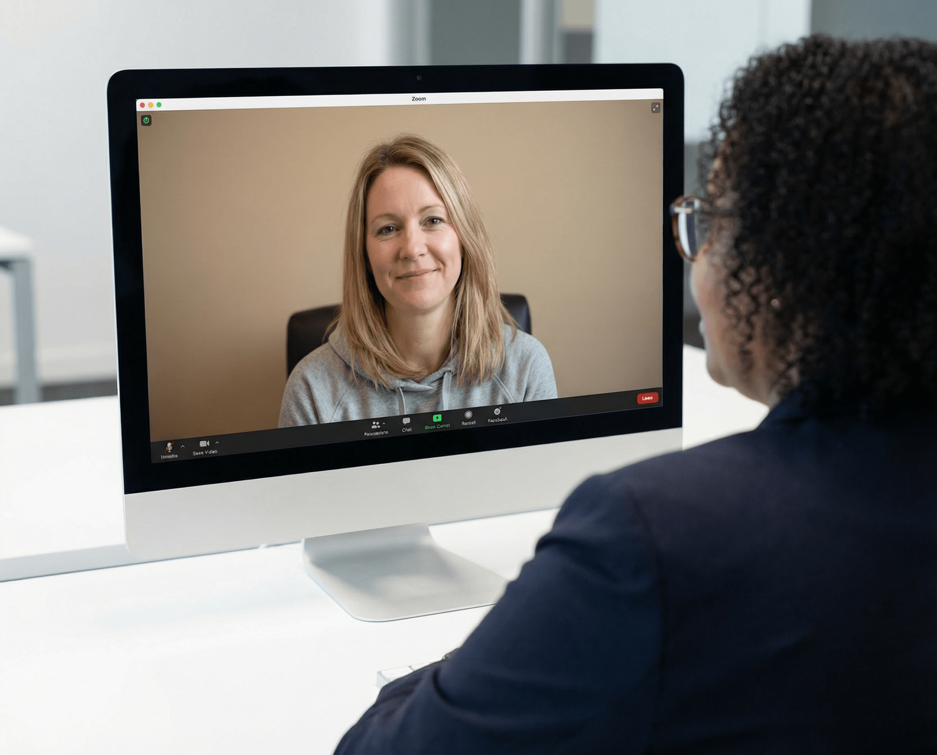 Person in suit on video call with smiling woman on computer screen.