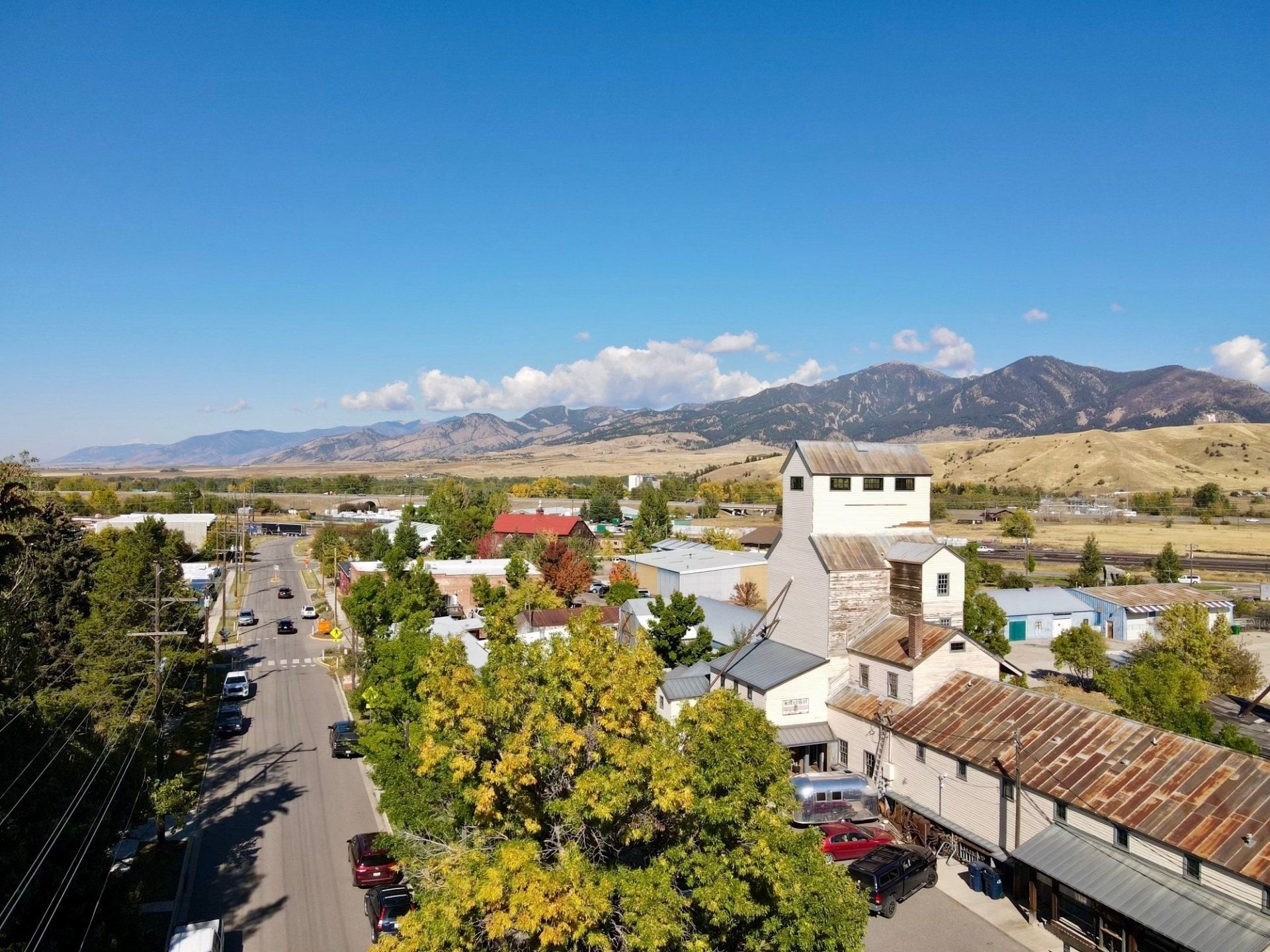 suburban neighborhood with a large building and road running through it with a view of the bridger mountains