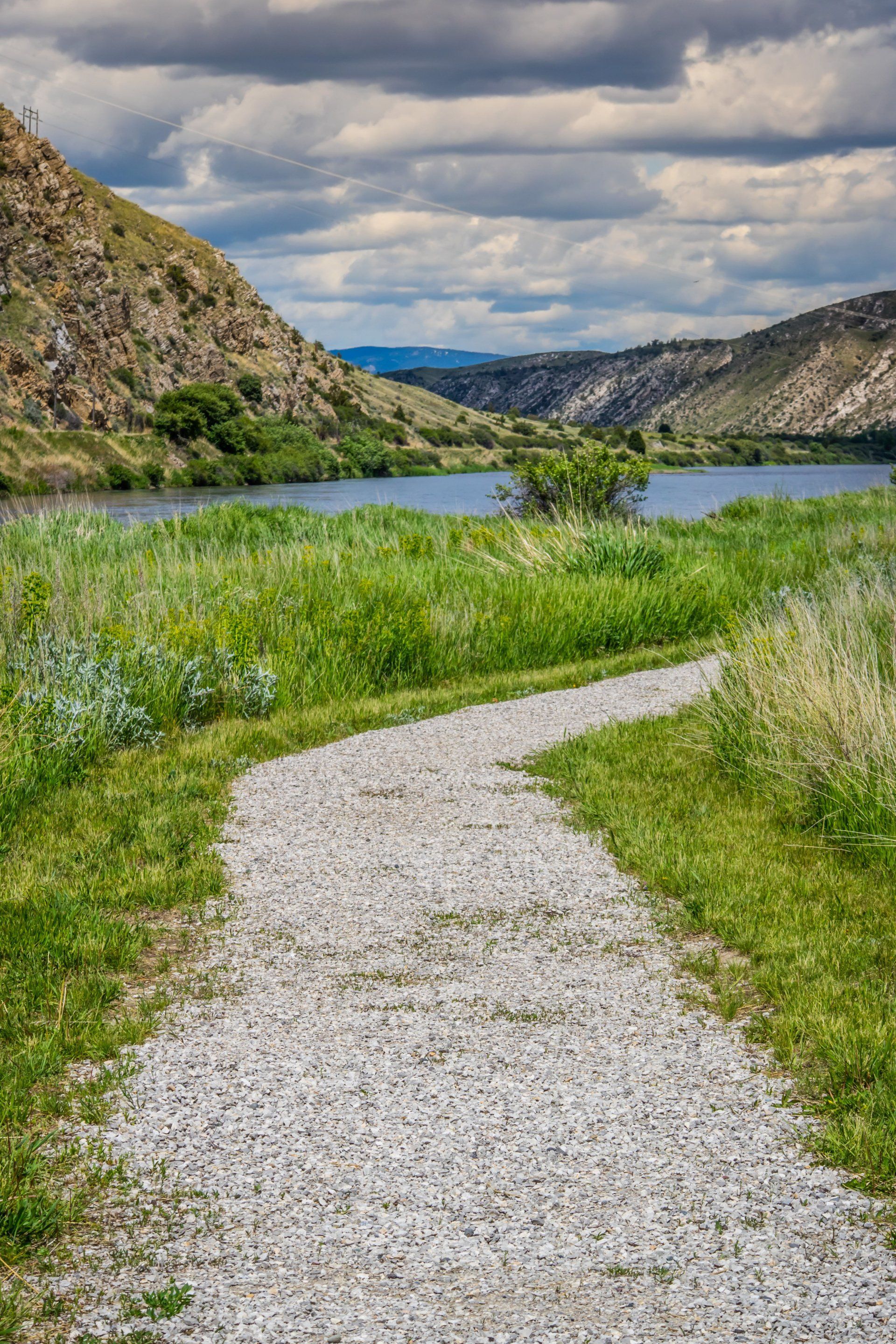 path looking down a valley with lots of green grass and mountains surrounding it
