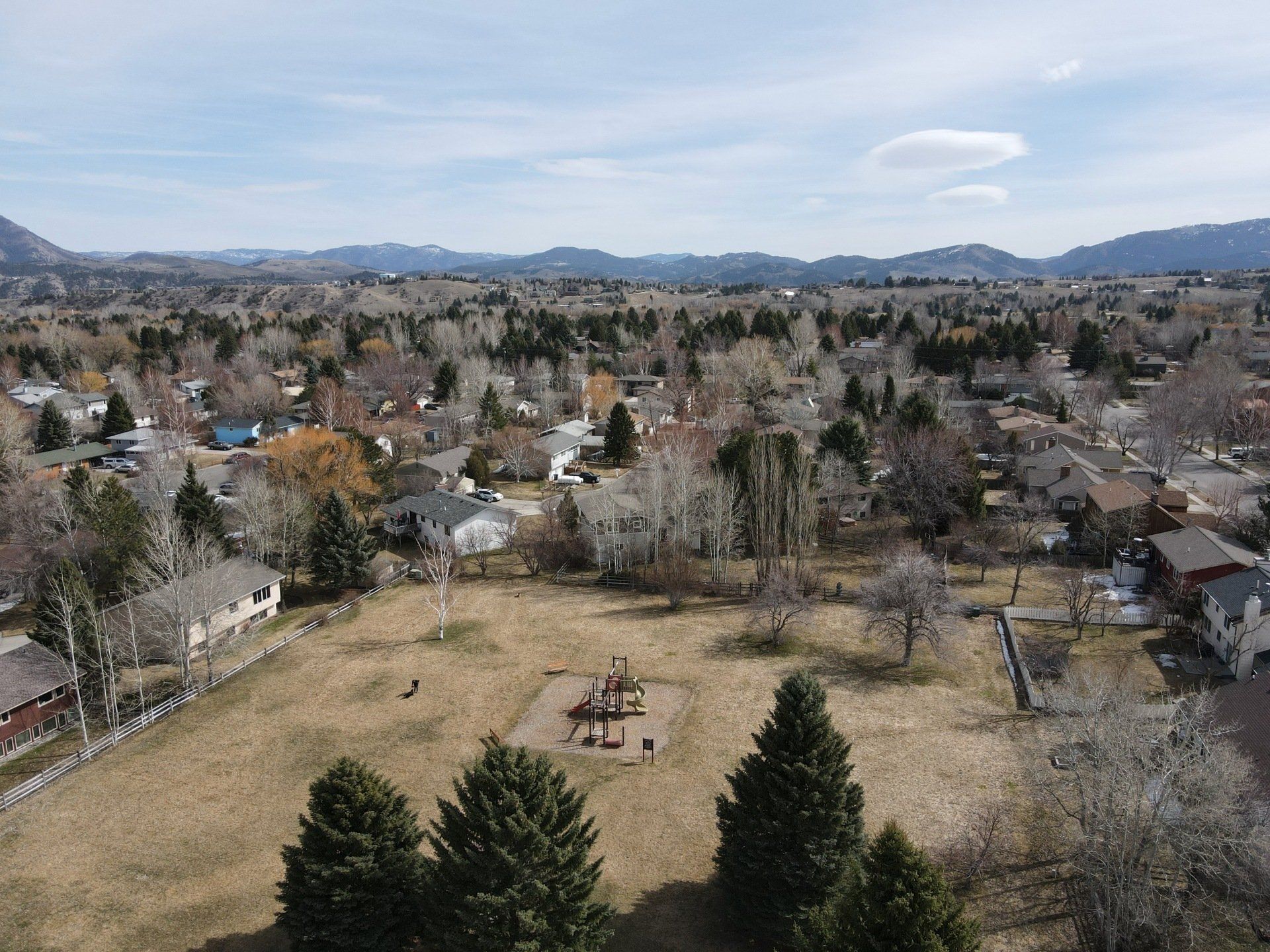 An aerial view of a park in a residential area with mountains in the background.