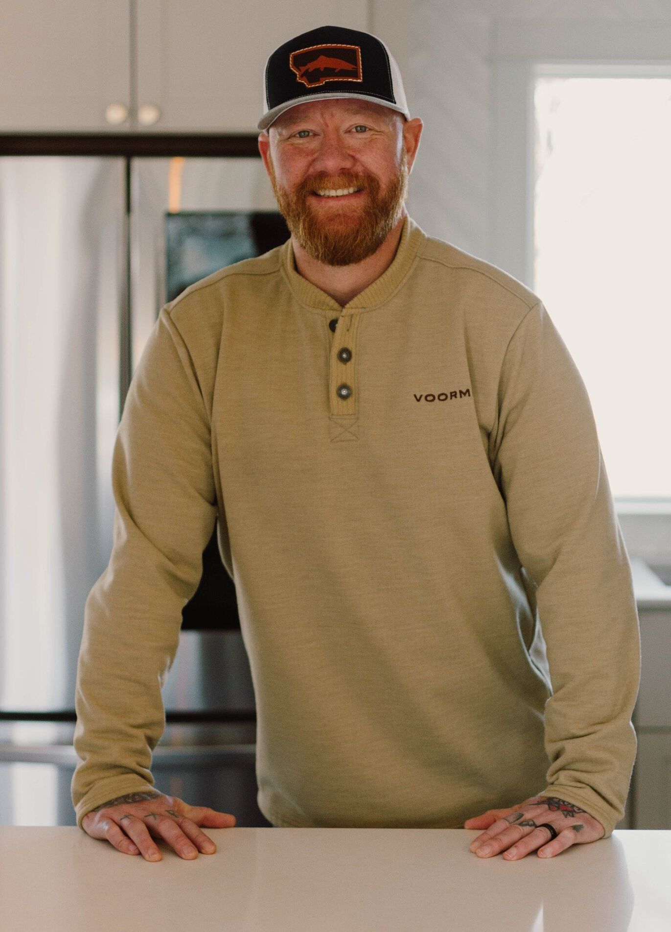 A man with a beard and a hat is standing on a counter in a kitchen.