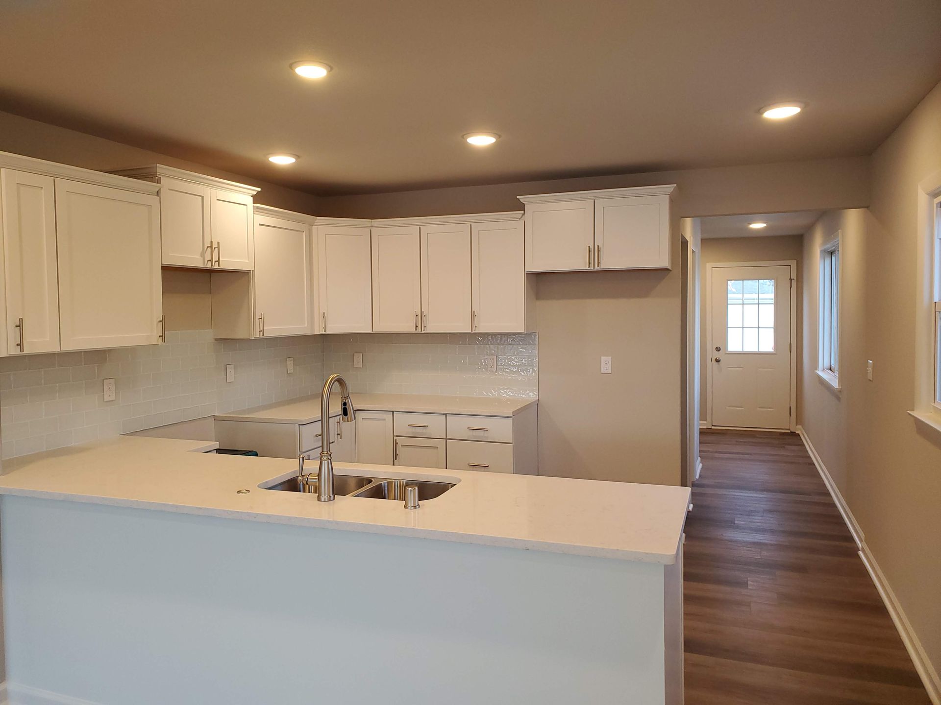 an empty kitchen with white cabinets and a sink .