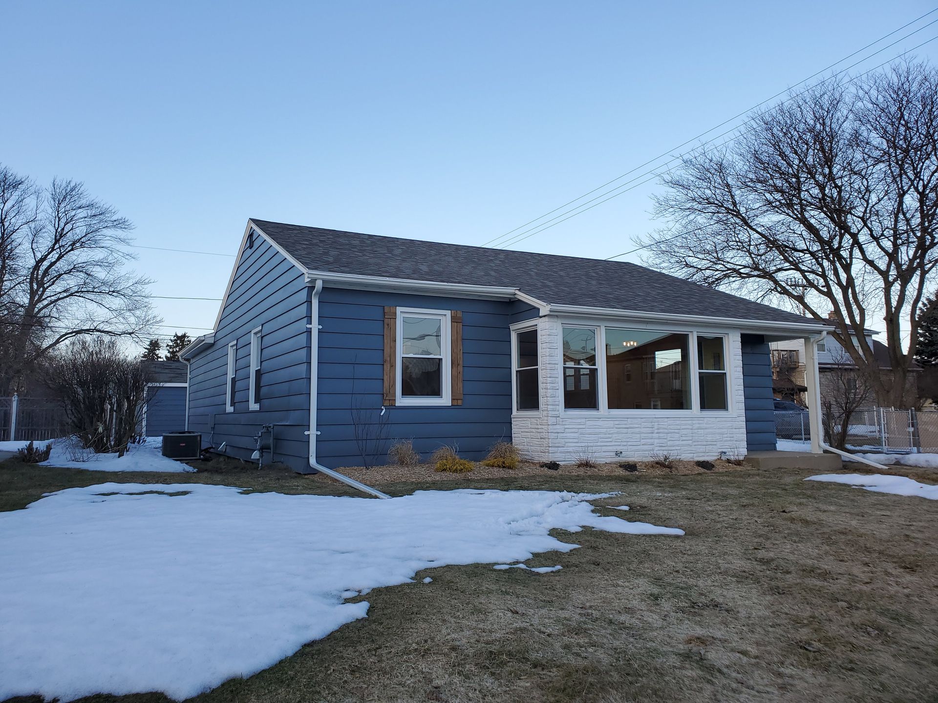 a blue house with snow on the ground in front of it