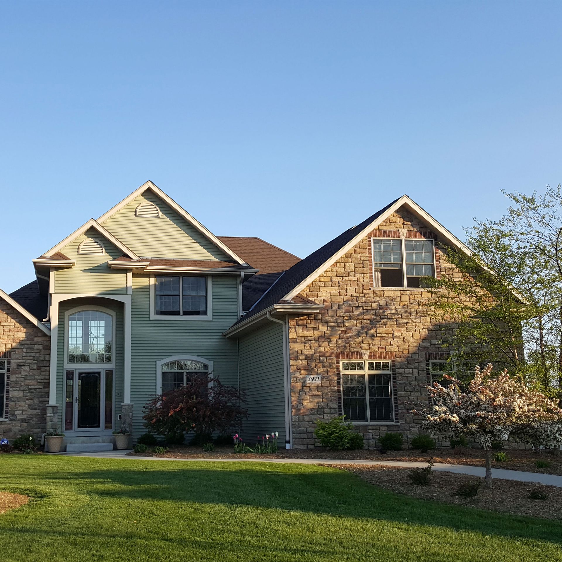 a white house with a green door is surrounded by trees and grass .