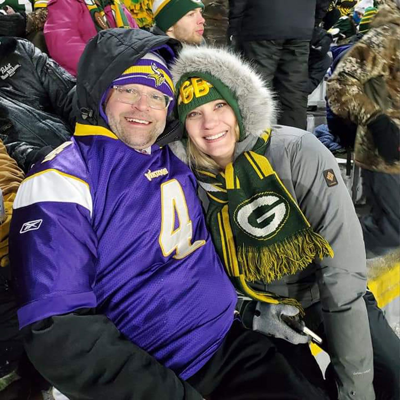a man and a woman are sitting next to each other at a football game .