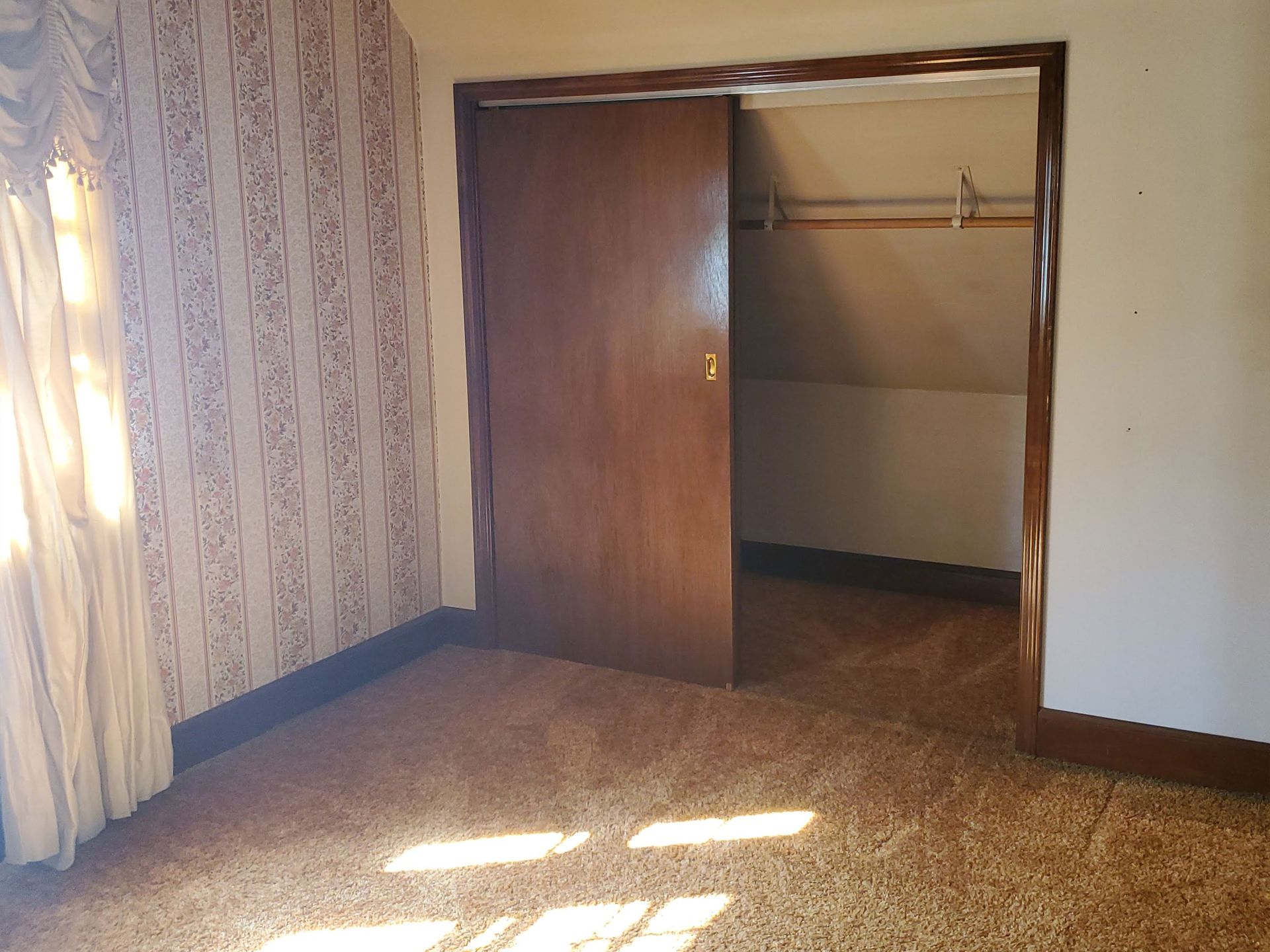 an empty basement with a carpeted floor and three windows .