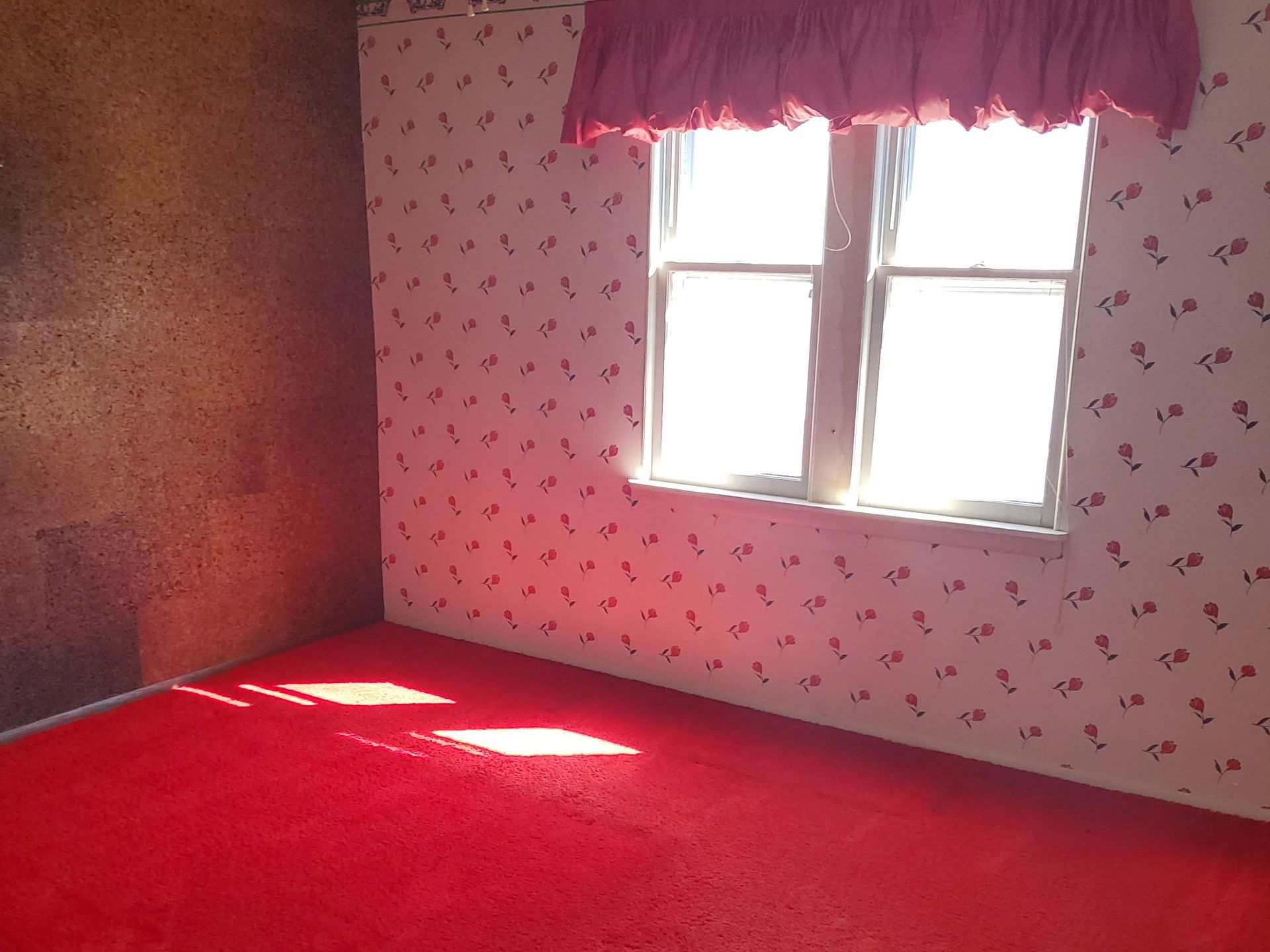 an empty room with a window and a carpeted floor .