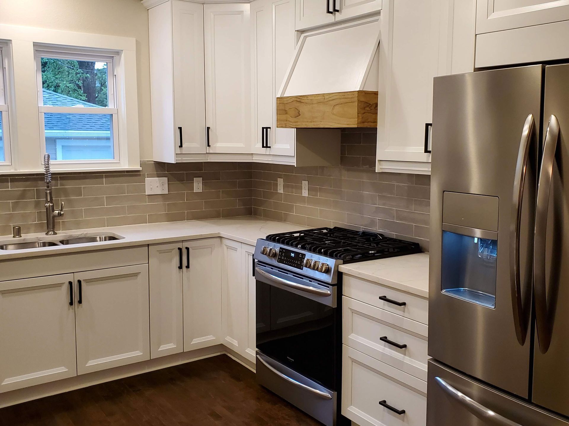 a kitchen with white cabinets , a stove , a refrigerator , and a sink .