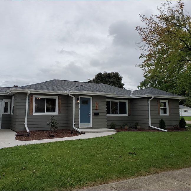 a gray house with a blue door and white windows