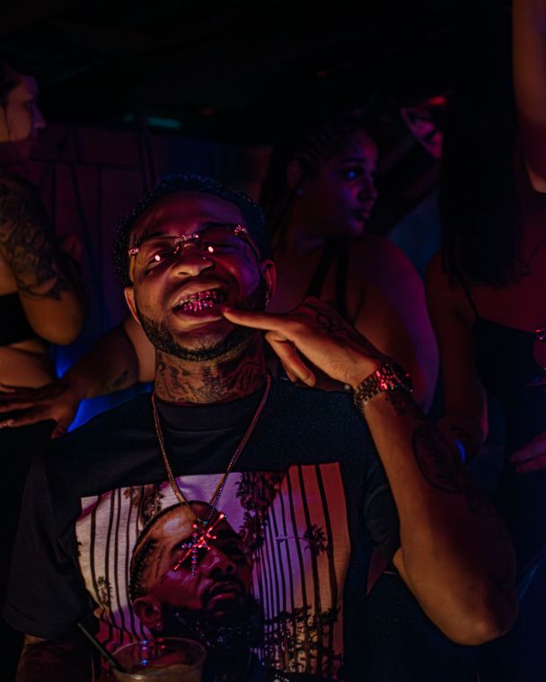 A man with a beard is making a funny face in a crowd of people at a party. Trevion500